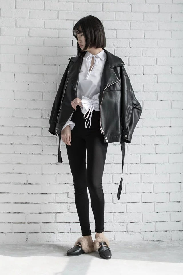 Woman wearing motorcycle jacket with belt and lapel collar