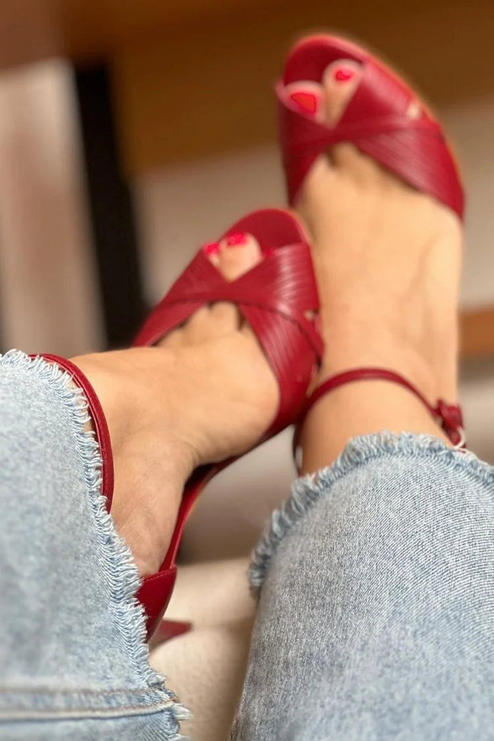 Woman wearing red stiletto heel sandals with braided straps