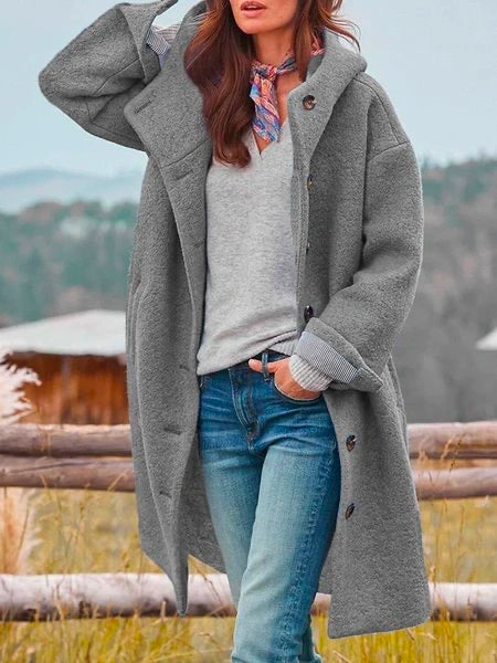 Woman wearing long hooded coat with button front