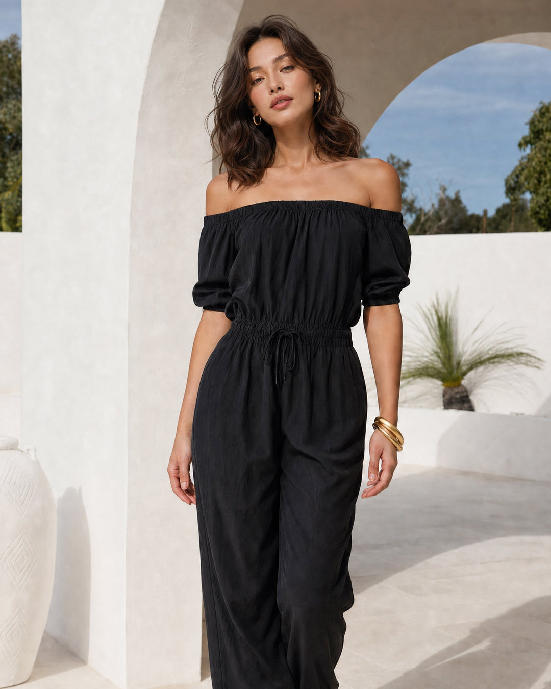 Woman wearing black off-shoulder sleeveless jumpsuit outdoors